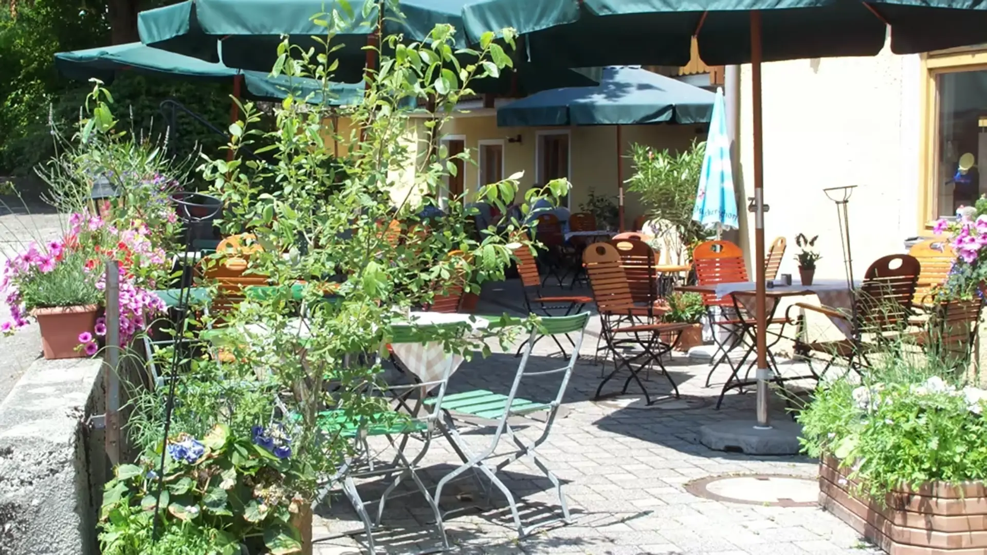 Sommerlicher Biergarten des Posthotels Pöcking mit blühenden Blumenkästen