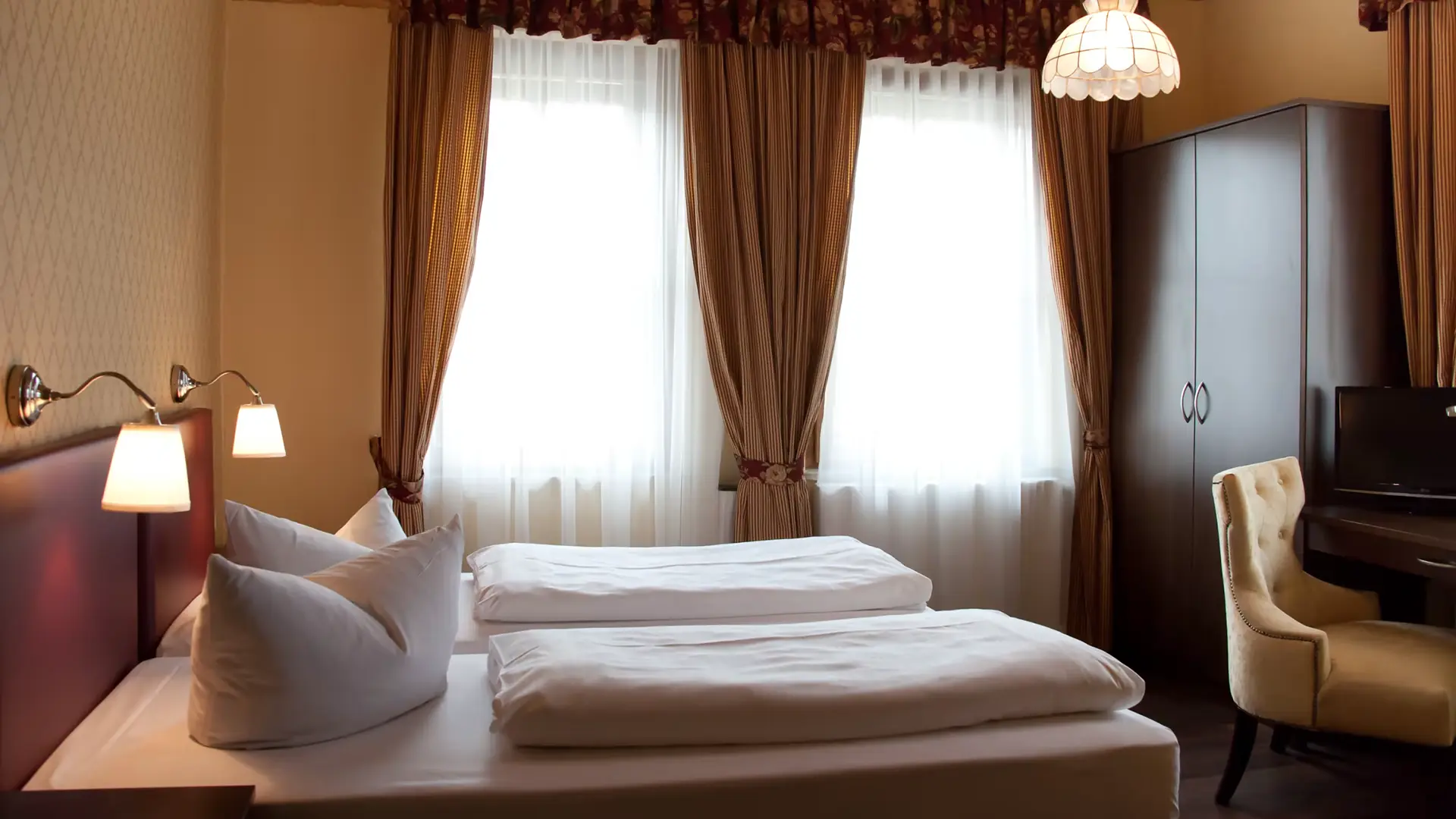 Doppelzimmer im Posthotel Pöcking mit Doppelbett, Sessel und Fenster zur Straße