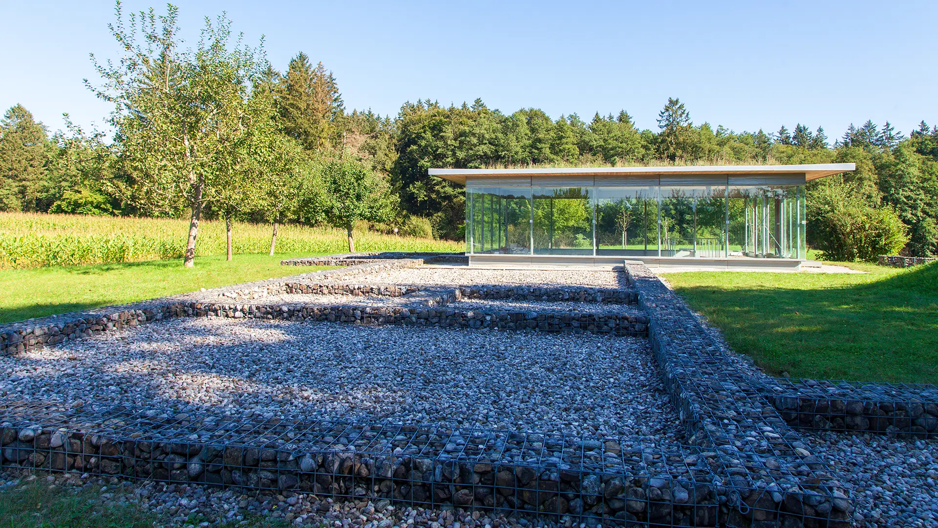 Glaspavillon über den Grundmauern der römischen Villa rustica bei Leutstetten, der Grundriss ist mit Steinkörben gestützt und nachgebildet.