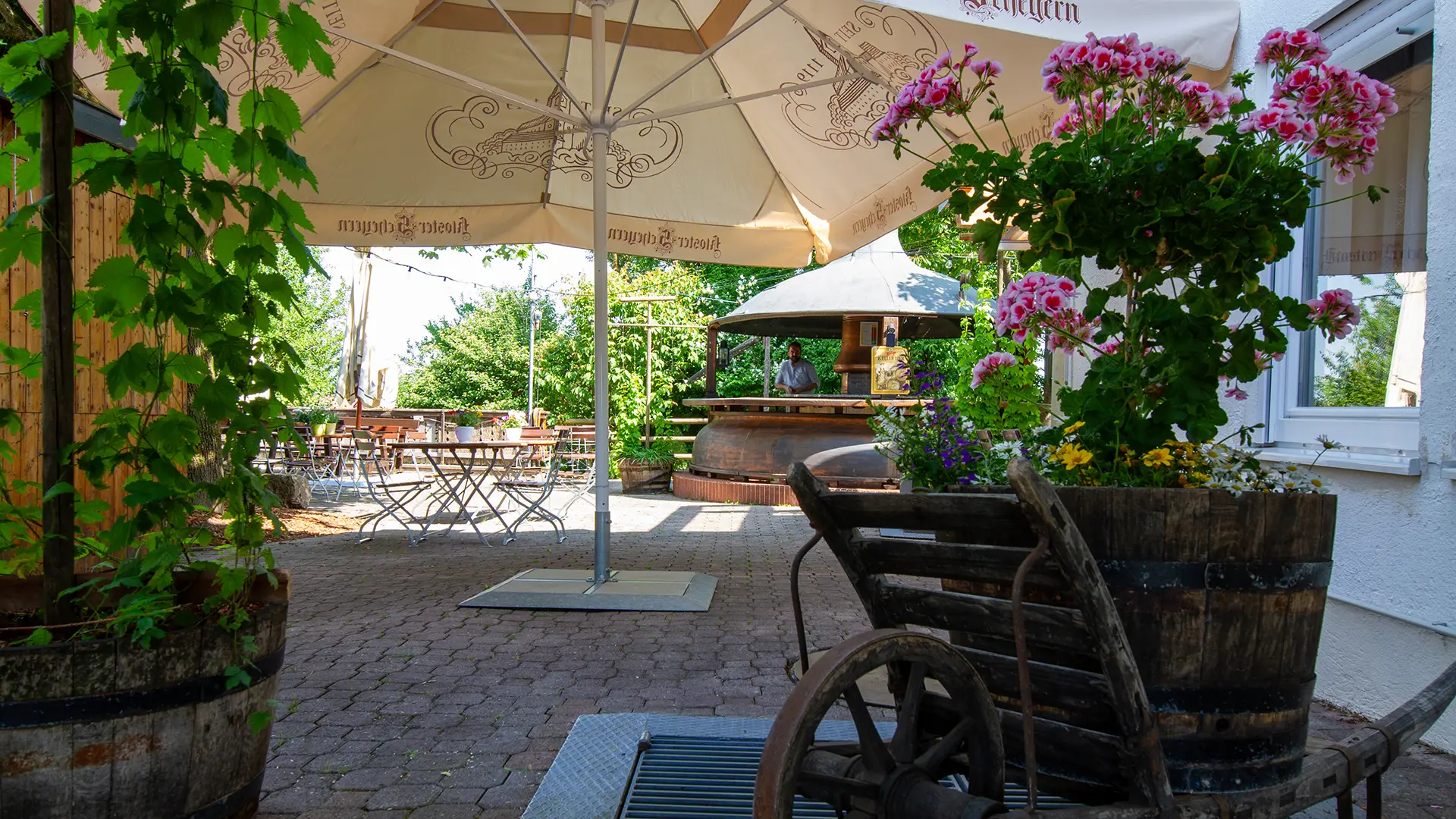 Eingang zum Biergarten mit Hotel Landgasthof Hipp weiße Schirme, viele Plfanzen und bayerische Gastlichkeit.