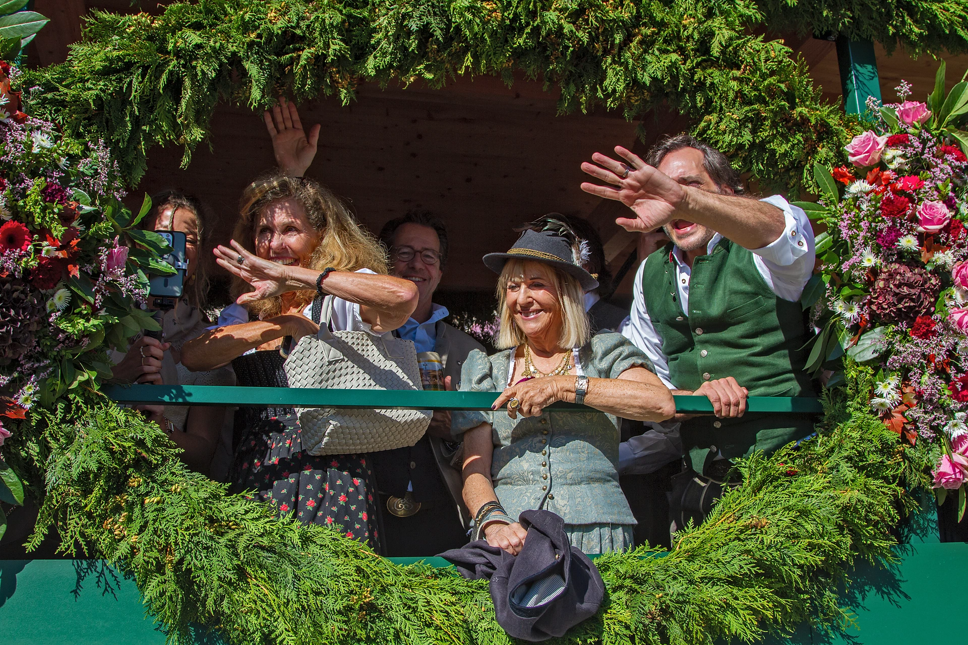 Frauen und Männer winken aus einem mit Tannengrün und Rosen umrahmten Festwagen der Käfer Wiesn-Schänke, Einzug der Festwirte auf dem Oktoberfest München