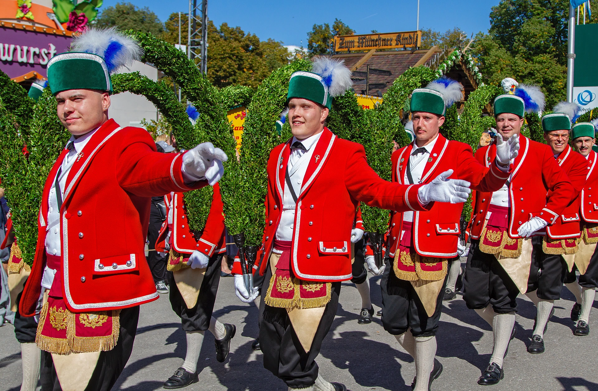Schäffler in roten Röcken, grünen Kappen und weißen Handschuhen marschieren in Reihe beim Einzug der Festwirte auf dem Oktoberfest München