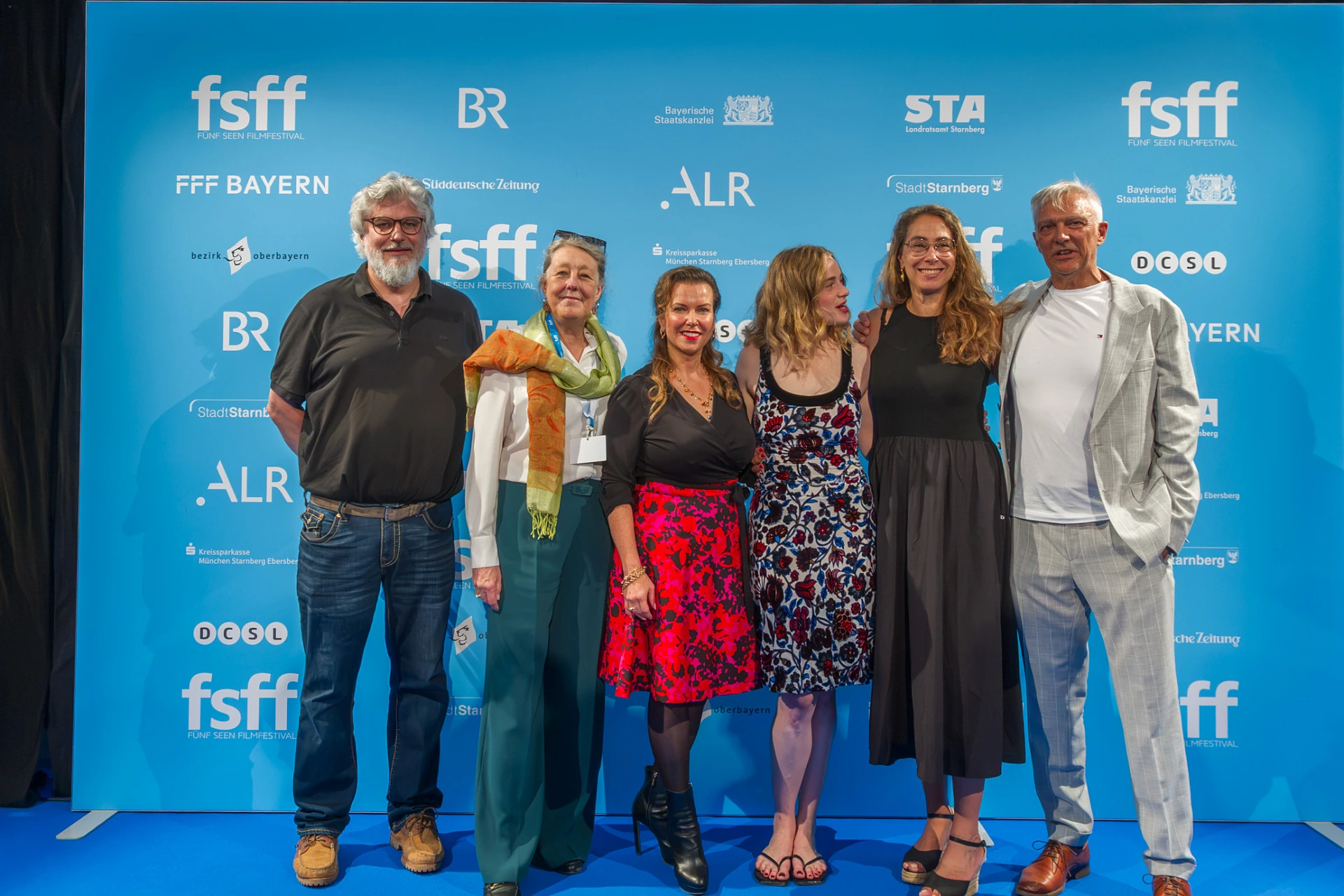 Sechs Personen vor der Fotowand des Fünf Seen Filmfestivals in Starnberg, von links Carsten Zehm, Christiane Falk, Susanne Zehm, Luna Wedler, Katalin Gödrös und Matthias Helwig