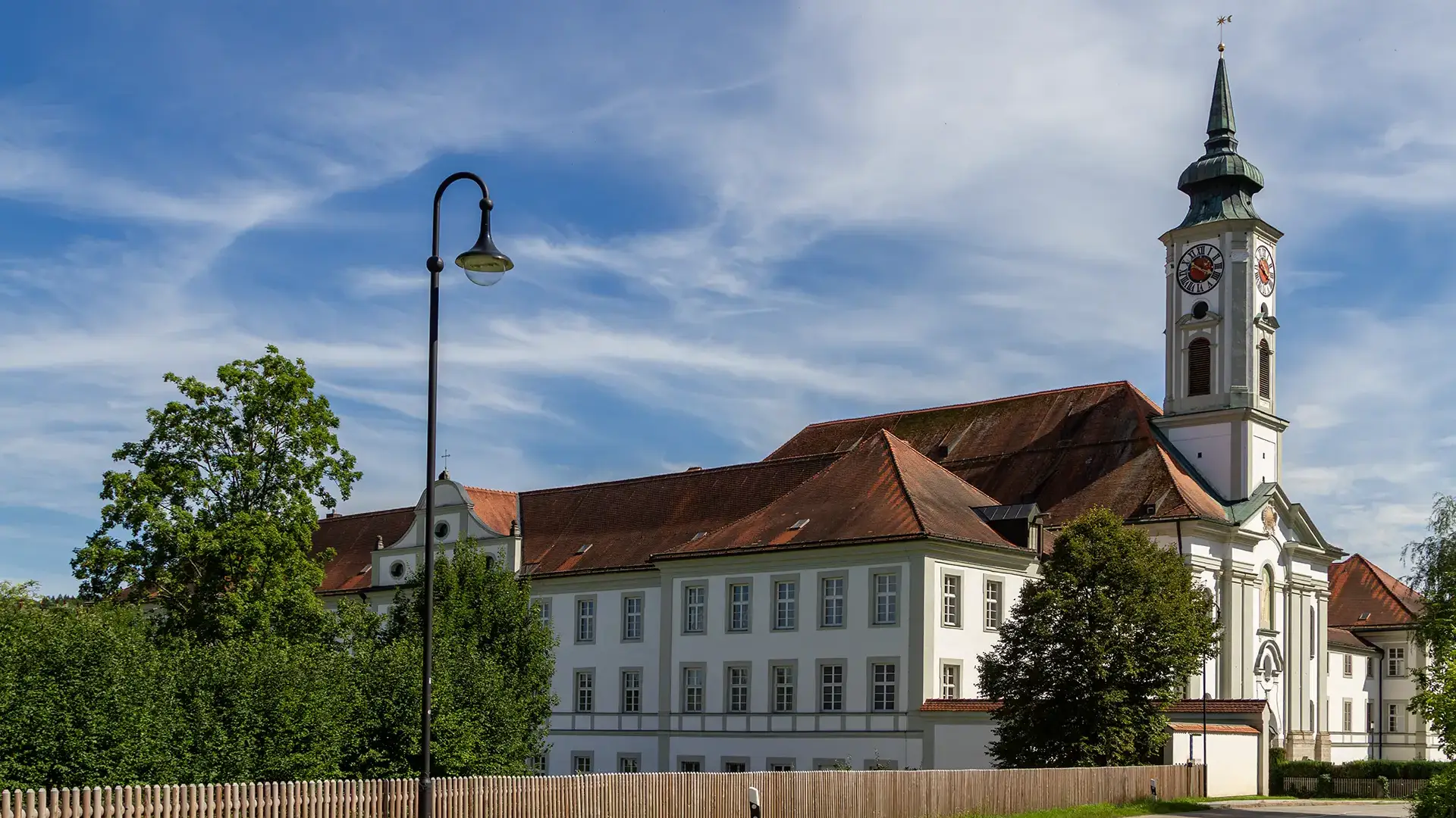 fuenfseen-kloster-schaeftlarn-rokkokokirche Kloster schäftlarn mit weiß blauem Himmel im Hintergrund - Blick von der Straße im Sommer