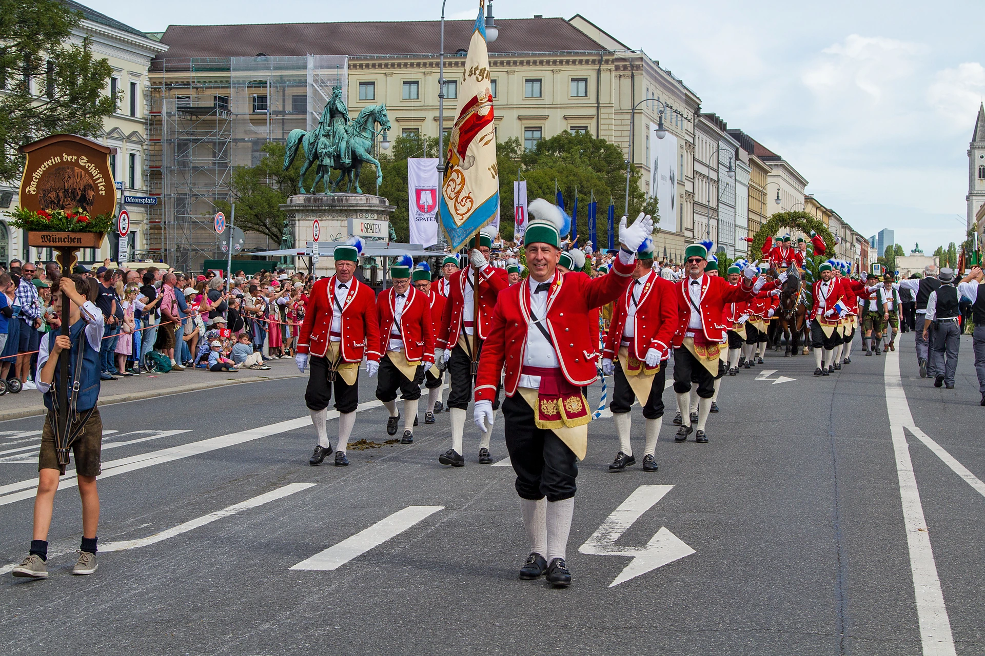 Schäffler in roten Röcken und grünen Kappen marschieren mit ihrer Fahne durch die Ludwigstraße, Trachten- und Schützenzug München