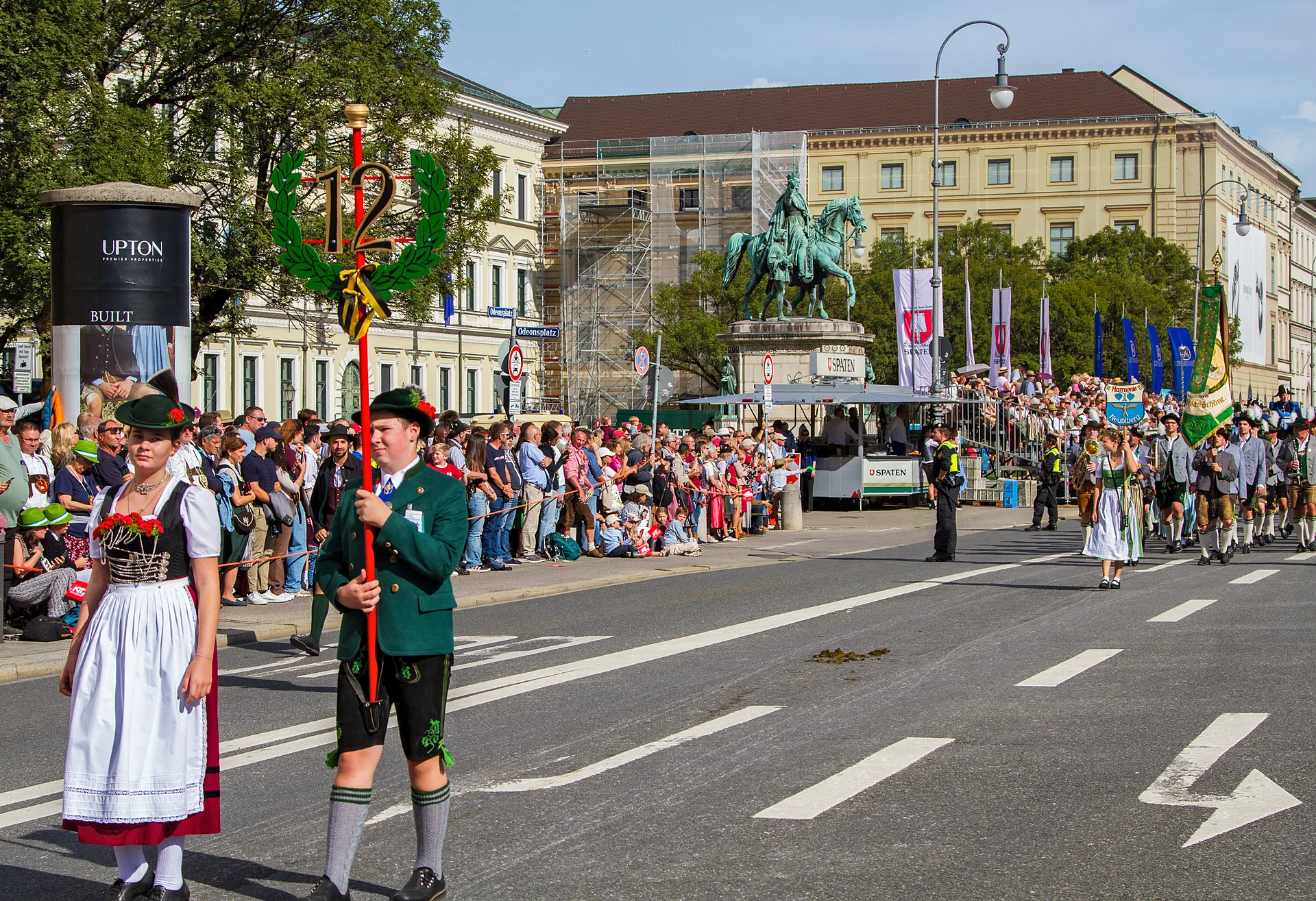 Ein Mädchen im Dirndl und ein Junge in Lederhose tragen das Zugschild mit der Nummer zwölf vor ihrer Gruppe, Trachten- und Schützenzug München