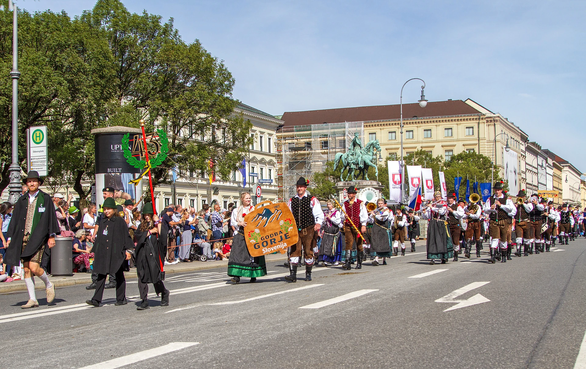 Taferlträger mit Zugschild vor einer Trachtengruppe mit großem Banner, Trachten- und Schützenzug München