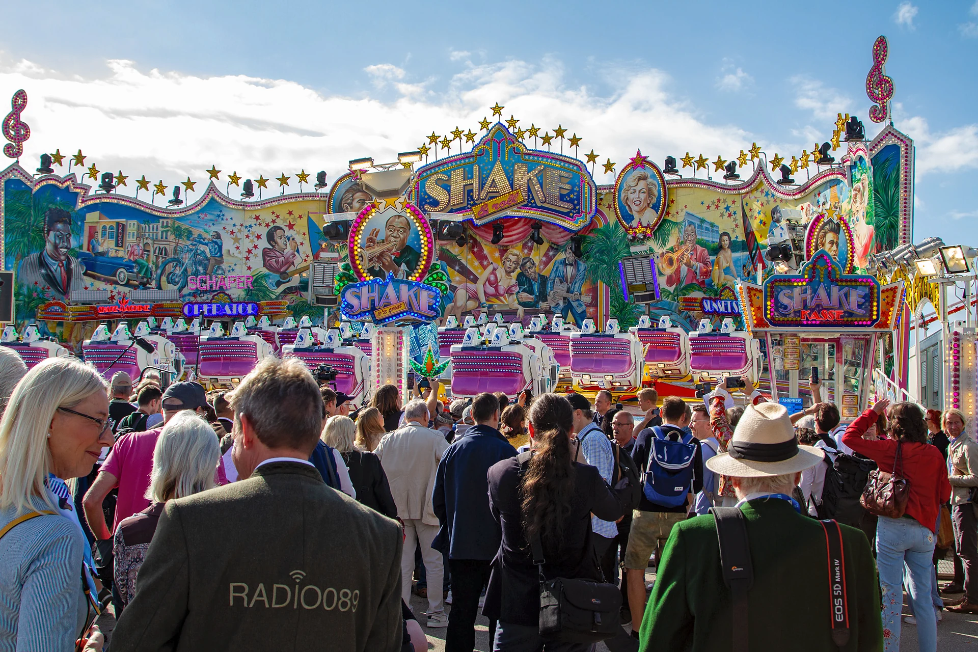 Journalistinnen und Journalisten stehen vor der bemalten Front des neuen Fahrgeschäfts Shake & Roll, Oktoberfest München