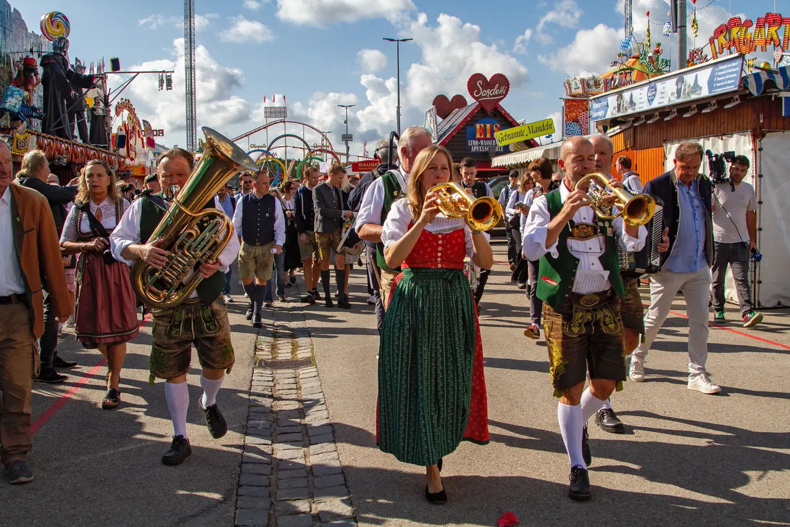 Musikerinnen und Musiker in Tracht spielen Tuba und Trompete und ziehen mit dem Pressetross über die Wiesnstraße, Oktoberfest München