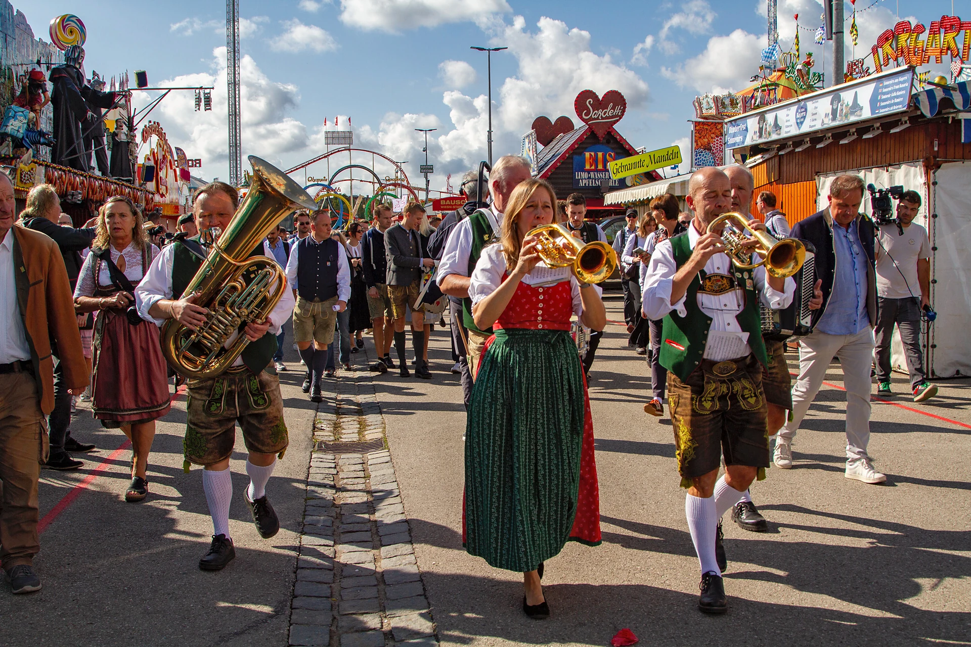 Musikerinnen und Musiker in Tracht spielen Tuba und Trompete und ziehen mit dem Pressetross über die Wiesnstraße, Oktoberfest München