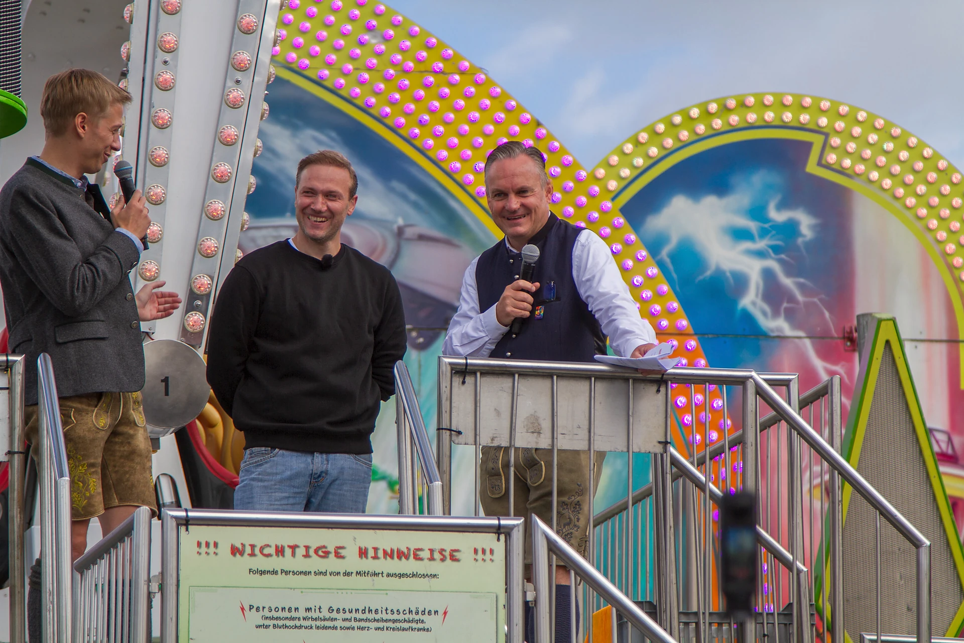 Oberbürgermeister Dominik Krause, Schausteller Willi Ottens junior und Wiesnchef Christian Scharpf stehen am Aufgang des Fahrgeschäfts Chaos Pendel, Oktoberfest München