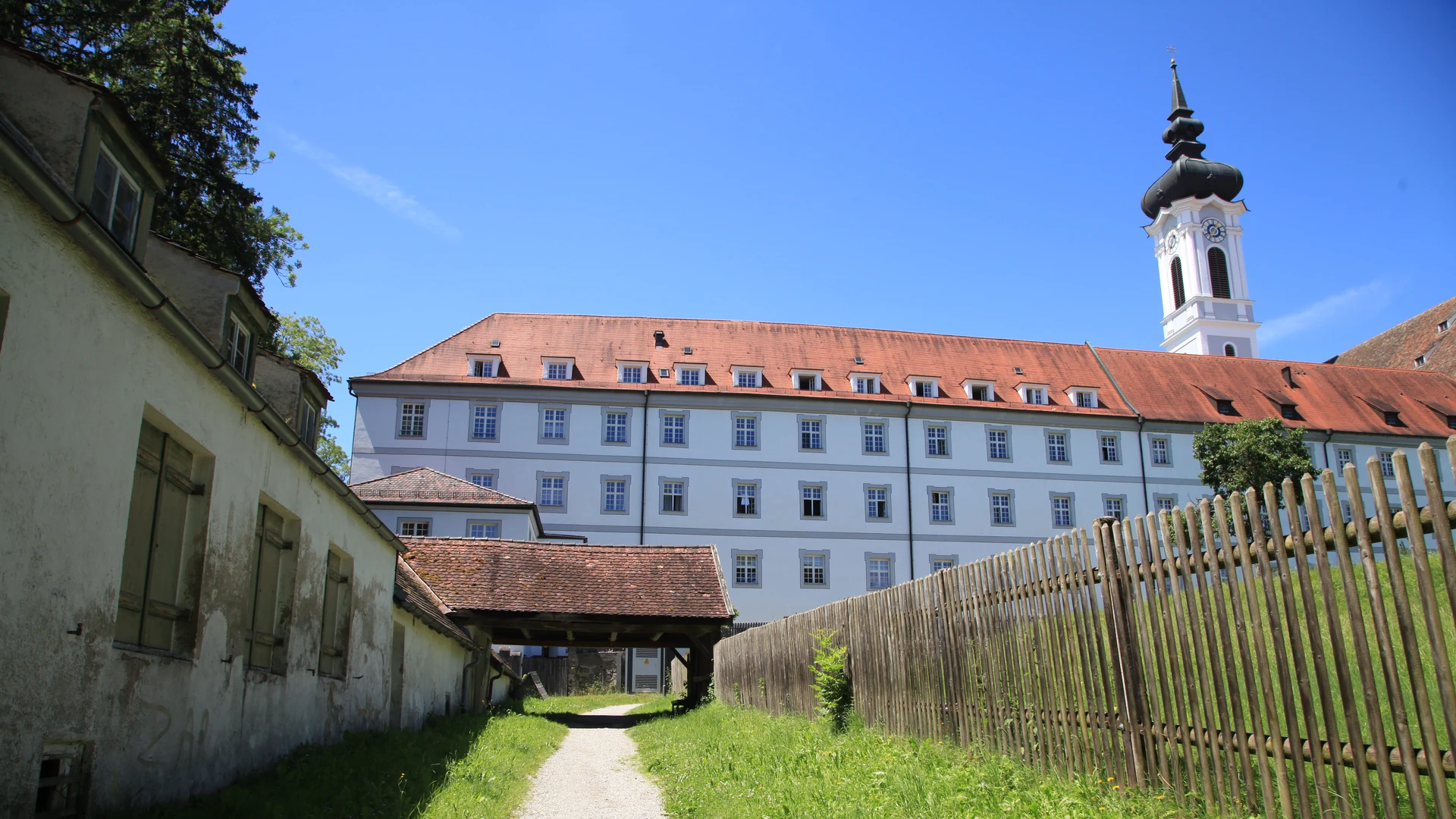 Klostergebäude und Kirche vom Marienmünster in Diessen, der Fußweg neben der Obstbaumwiese vorbei am Grab der Heiligen Mechthild