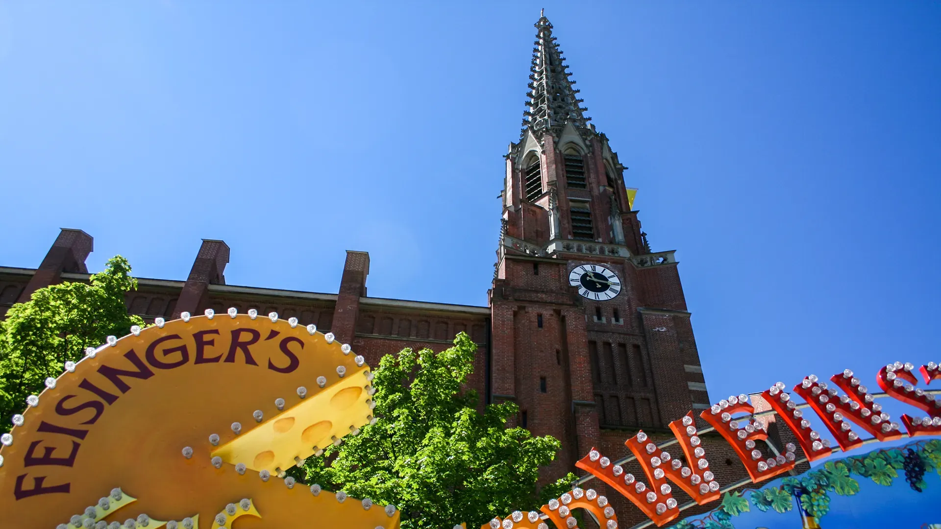Kirche am Maria Hilfplatz bei der Auerdult. Im Vordergrund Feisinger's Käselogo und Leuchtreklame