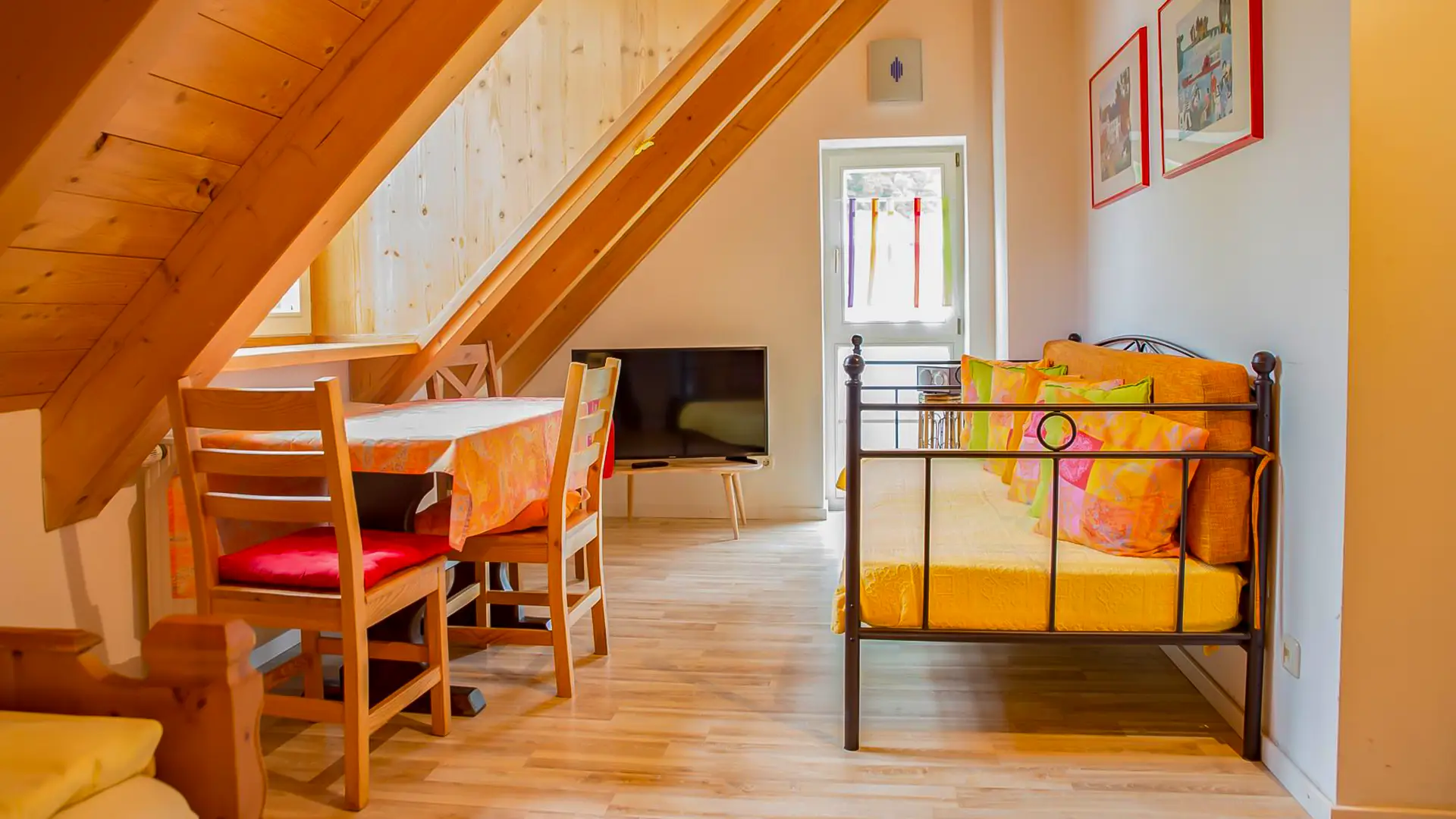 Ferienwohnung Schmetterling mit Schlafcouch, Küchentisch mit Stühlen, Fernseher, Dachschräge mit Holzdecke, kante von Bett Thamm Ferienwohnungen.
